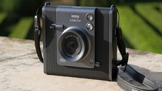 The Instax Wide Evo Hybrid Instant Camera sitting on a concrete bench in bright sunlight.