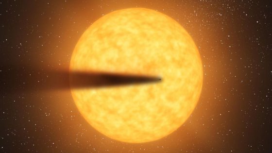 An illustration of a small, dark planet leaving a tail of disintegrating matter behind it as it passes in front of a large star