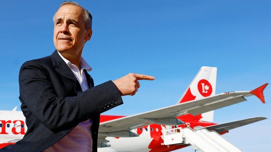 Canada's Prime Minister Mark Carney gestures to an aeroplane.