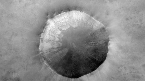 A photograph taken from the Mars Reconnaissance Orbiter, which shows wave-like patterns inside a Mars crater. 