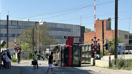 Vrachtwagen rukt bovenleiding af en kantelt op spooroverweg: grote hinder, twee treinen zonder airco staan stil