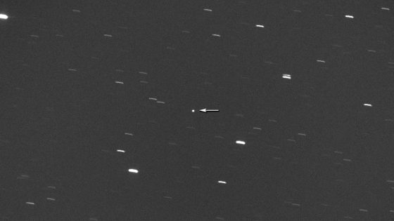 An image showing the potentially hazardous asteroid 2008 DG5 indicated by a white arrow against a dark sky dotted with star lines.