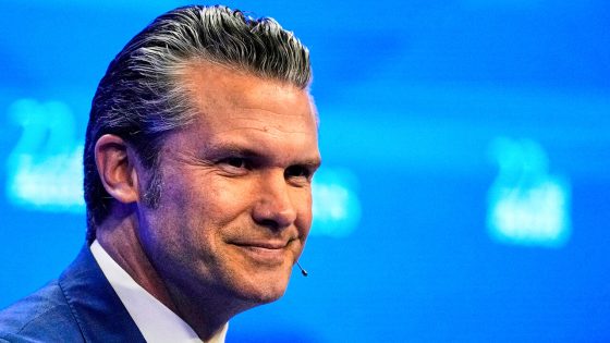 US Defense Secretary Pete Hegseth smiles on stage whilst deivering a speech