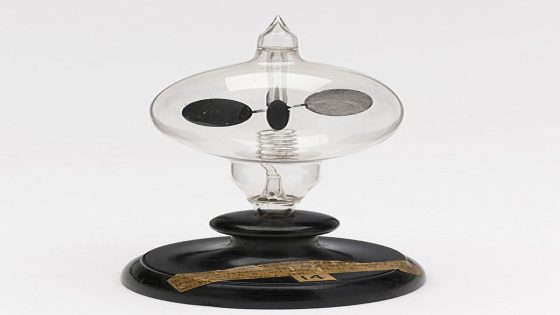 Image of a wooden stand holding a sealed glass bulb with a spinning set of vanes, each of which has a lit and dark side.
