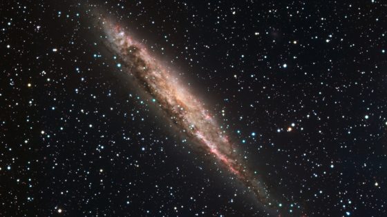 A spiral galaxy is tilted at a 45 degree angle amidst stars in space. 