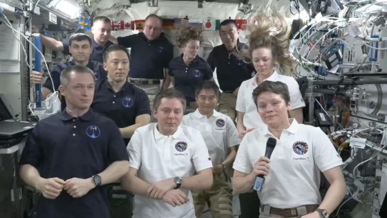11 people stand in a cramped space station module during a farewell ceremony